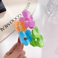 Pink acetate flower hair claw clip held by hand against a minimalist white desk - 8.5cm / Four Color Flowers
