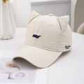 Süße beige Baseballkappe mit Katzenohren und blauer Stickerei auf einem hellen Hintergrund - Milchweiß