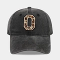 Macro detail of leopard print letter O embroidery on washed black cotton baseball cap - Letter O
