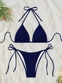 Flat lay of navy blue ribbed string bikini with sunglasses and tropical leaves on white fabric - Navy Blue