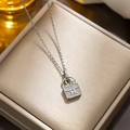 Silver necklace with diamond-encrusted H-letter handbag pendant on gold jewelry display - 8872 Steel Color H Bag