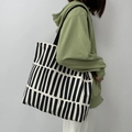 Grand sac fourre-tout en toile à rayures noires et blanches porté à l'épaule par un mannequin - Impression Complète à Rayures