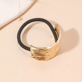 Dettaglio dell'elastico per capelli nero con placca in metallo dorato effetto onda - Modello Elastico / Nero/Oro