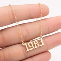Macro shot of 1983 year pendant in gold finish on a fine chain held by hand - 1983 / Gold