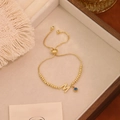 Adjustable golden bracelet featuring a crystal letter M and blue evil eye charm - Letter M