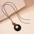 Détail du pendentif en résine noire avec perle oeil de tigre sur un long collier cordon - Style de Perle à Texture Brune