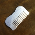 Handcrafted fish-shaped seashell hair comb with iridescent luster on a beach - Double Fish Comb