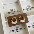 Dettaglio degli orecchini a cerchio in smalto arcobaleno su supporto in legno - Cerchio Arcobaleno Oro 18K
