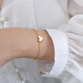 18k gold plated stainless steel bracelet with white pearl heart pendant on model - Gold White Shell Bracelet