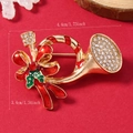 Vue macro de la broche cor de Noël avec émail rouge et strass sur un fond de fête rouge - Corne (WBR287)
