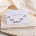 Tre paia di orecchini a lobo in acciaio dorato con zirconi su sfondo di marmo - Set di Lobo in Zirconia Bianca Oro