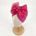 Rose red baby turban hat with a large gold polka dot bow on a fabric display model - Purplish Red