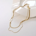 Collar de doble capa en malla de serpiente dorada sobre un plato de cerámica blanca - Dorado