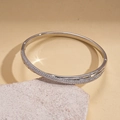 Detail showing pave-set white zircons on silver-plated bangle against stone texture - Silver