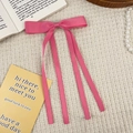Close-up of a rose red satin ribbon bow hairpin with long tassels on waffle texture fabric - Rose Pink