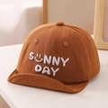 Detailed view of Sunny Day embroidery on a soft-brim baby sun hat in caramel brown cotton - 50cm / Coffee