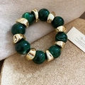 Close-up of emerald green marble beads and irregular gold metal segments on bracelet - Green-Gold