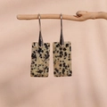Detailed view of beige spotted rectangle stone drop earrings hanging on a wood branch - Dalmatian Stone Silver Hook