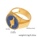 Detail eines 18k vergoldeten Edelstahlrings mit blauem Öltropfen und Engelsrelief - Gold-Blau Emaille