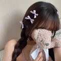 Close-up of light purple mini bow hair clips styled on model's braided hair - Purple
