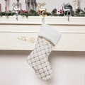 Christmas stocking with gold sequin plaid and white faux fur cuff hung by a fireplace - White