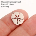 Silver stainless steel sand dollar charm 12x13mm shown on fingertip for scale - Sand Dollar / Silver