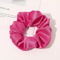 Close-up of a large fuchsia silk scrunchie with a glossy satin texture and dense pleats - Rose Red