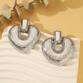 Macro detail of silver heart earrings featuring artistic vertical textured metal finish - Striped Large Heart Silver (0536)