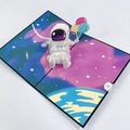 Dettaglio di un biglietto 3D pop-up con astronauta, palloncini colorati e tema spazio - Biglietto Astronauta