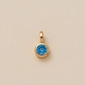 Close-up of golden circular pendant with a round faceted blue gemstone in bezel setting - Round March Pendant (Light Blue)