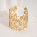 Dettaglio di un ampio bracciale a polsino dorato con motivi floreali geometrici traforati - Oro Cavo