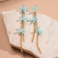 Dettaglio di orecchini a nappa con petali di resina blu, perline e catena d'oro - Blu