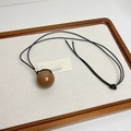 Close-up of a large brown resin sphere pendant on a black cord within a wooden tray - Smooth Ball Pendant (Z-3126)