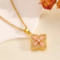 Gros plan d'un pendentif marguerite doré avec cristal rose sur un tissu en satin - Collier Fleur à Quatre Feuilles Ajourée Doré avec Zircone Rose (T024)