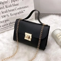 Black litchi pattern small chain bag with gold rotary lock on white plush rug - Black