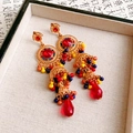Detalle de pendientes bohemios vintage con borlas y cuentas de colores en un joyero - Dorado Rojo