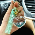 Mint green strap keychain with a liquid quicksand acrylic heart charm and gold bell - Green