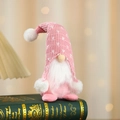 Macro detail of sitting Christmas gnome with pink heart-pattern knitted hat and plush beard - Pink