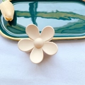 Matte cream flower claw clip with a frosted finish on an elegant textured background - Nude