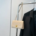 Cream white quilted crossbody bag with gold lock and chain strap on clothing rack - White