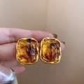Detail of elegant gold earrings with amber resin stones held between fingers - 23# Silver Pin Gold Brown Rectangular