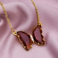 Close-up of butterfly pendant necklace with dark red crystal wings and gold chain - Coffee