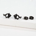 Macro detail of matte black cartoon pig stud earrings with hollow heart shape cutouts - Pig / Black