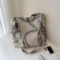 Borsa tote in tela minimalista con motivi geometrici a linee nere in un ambiente interno - Curva