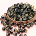 Macro shot of 10mm black and gold crackle glass beads on a pink background - Cool Gold