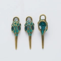 Three vintage bronze bird skull pendants for DIY jewelry making in a flat lay view - Antique Green
