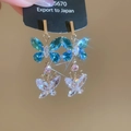 Detail von zweilagigen Schmetterlingsohrringen mit blauen und klaren Kristallen in Gold - Schmetterling-Anhänger / Blau