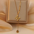 Detailopname van gouden halsketting met letter M en kubuskwastje op satijnen stof - Letter M (WY006-M)