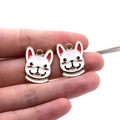 Macro view of white enamel French Bulldog charms held between fingers for size reference - French Bulldog