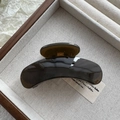 Detailed view of a dark brown glossy hair claw clip on a wooden jewelry display tray - Fruit Grey